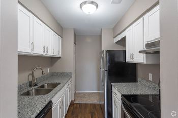 Galley kitchen with granite counters, white cabinets and stainless appliances